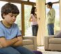 A child in-focus slouching in the foreground with parents arguing out-of-focus in the background