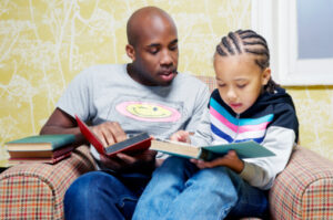 A father and son reading books on chair