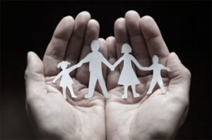 Two hands holding paper cutouts of a family holding hands