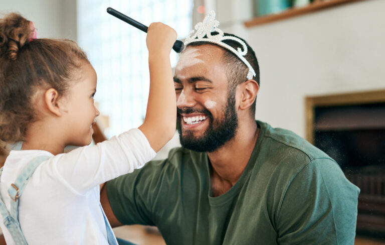 Shot of a little girl putting makeup on her father while playing together at home.